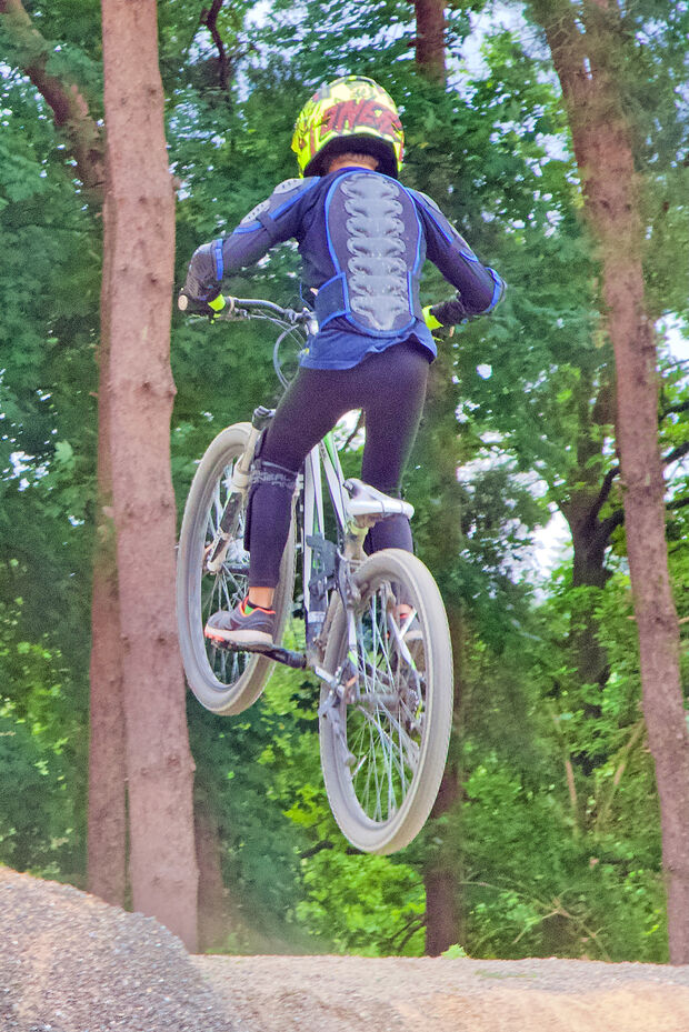 Das kleine Wäldchen am Freibad bildet die grüne Kulisse für den neuen Bike-Park der Gemeinde Wickede (Ruhr). – Hier ein Junge mit Schutzkleidung beim Sprung mit seinem Mountainbike über die Hügel.  FOTO: ANDREAS DUNKER
