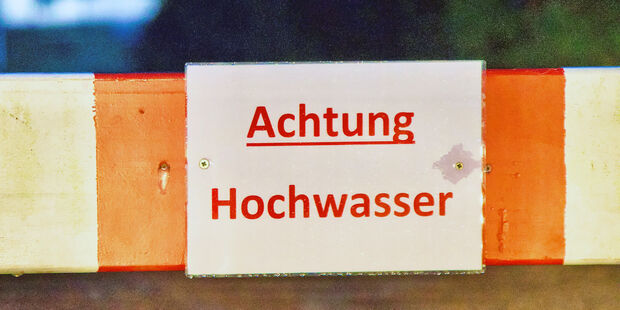 An der überfluteten Straße am Obergraben am Freibad warnte die Gemeinde vor dem Hochwasser mit einem Schild an einer Absperrbarke. FOTO: ANDREAS DUNKER