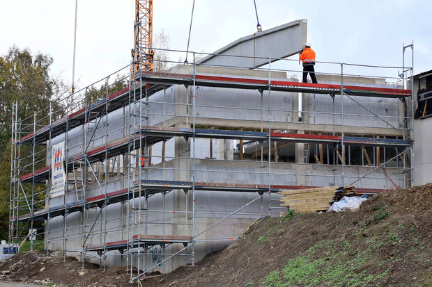 Bauarbeiter setzen die schwebenden Fertigbetonteile passgenau in den Rohbau als Erweiterung des bestehenden Aldi-Marktes ein. FOTO: ANDREAS DUNKER