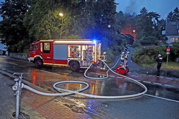 Die Feuerwehr baute eine Wasserversorgung von der Fröndenberger Straße zum Einsatzort an der Bergstraße 51/53 auf. Im Hintergrund erkennt man den Schein der hoch lodernden Flammen. FOTO: ANDREAS DUNKER