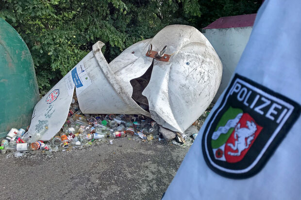 Ein Polizei-Beamter am Tatort: Der Altglas-Container am Kommunalfriedhof ist völlig zerstört. FOTO: ANDREAS DUNKER