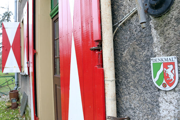 Die markanten rot-weißen Fensterläden des Herrenhauses und die nordrhein-westfälische Denkmalplakette am Herrenhaus FOTO: ANDREAS DUNKER