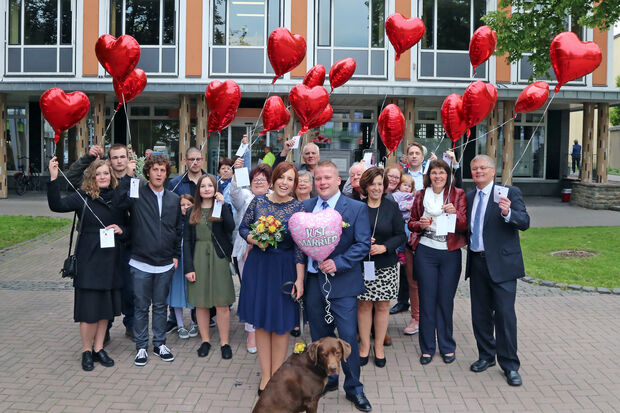 Das Brautpaar mit Hund "Louis" und der restlichen Hochzeitsgesellschaft mit roten Herz-Luftballons vor dem Wickeder Rathaus FOTO: ANDREAS DUNKER