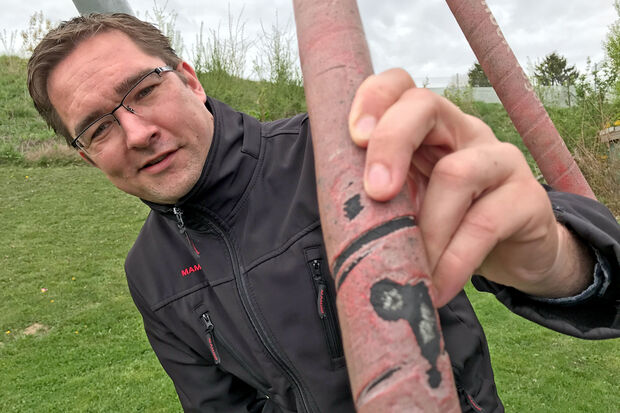 Daniel Luig vom Ordnungsamt der Gemeinde zeigt die "Schnittverletzungen" in einem Schutzschlauch um die Kette eines Spielgerätes. FOTO: ANDREAS DUNKER