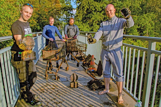 Die beiden 27-jährigen Wickeder Metall-Angler Dennis Keggenhoff (links) und Dominic Ihme (rechts) bekamen jetzt Unterstützung bei der Bergung von Altmetall aus der Ruhr durch zwei Schrott-Taucher aus Soest (hinten). Zusammen förderte das Quartett unter anderem zwei alte Einkaufswagen von EDEKA aus dem Obergraben des Flusses. FOTO: ANDREAS DUNKER