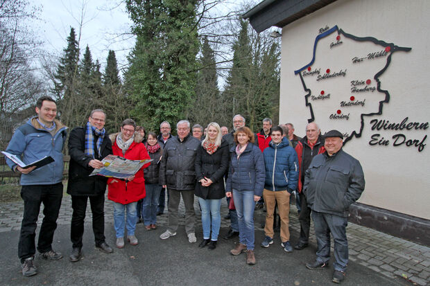 Das Wimbern ein Dorf mit vielen kleinen verstreuten Siedlungen ist, macht ein Relief an der Schützenhalle der St.-Johannes-Bruderschaft deutlich. Hier zu sehen mit einer Gruppe von Bürgern, die sich auf Einladung der Gemeinde an einem Ortsrundgang beteiligten. ARCHIVFOTO: ANDREAS DUNKER