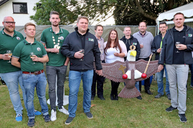 Jungschützen-Offizier Tobias Belz, der alte Jungschützenkönig Louis Eickenbusch, der neue Jungschützenkönig Niklas Kittling, Lars Velmer, das Königspaar Timo Eickenbusch und Tanja Sczesny, Kommandeur Andreas Schacke, Vogelbauer Andreas Westhoff, Oberst Stefan Reszel und André Robbert (von links) nach der Taufe des Holzadlers auf den Namen "Klabautermann". – In einer Kneipe dieses Namens hatte sich das amtierende Schützenkönigspaar kennen gelernt. FOTO: ANDREAS DUNKER